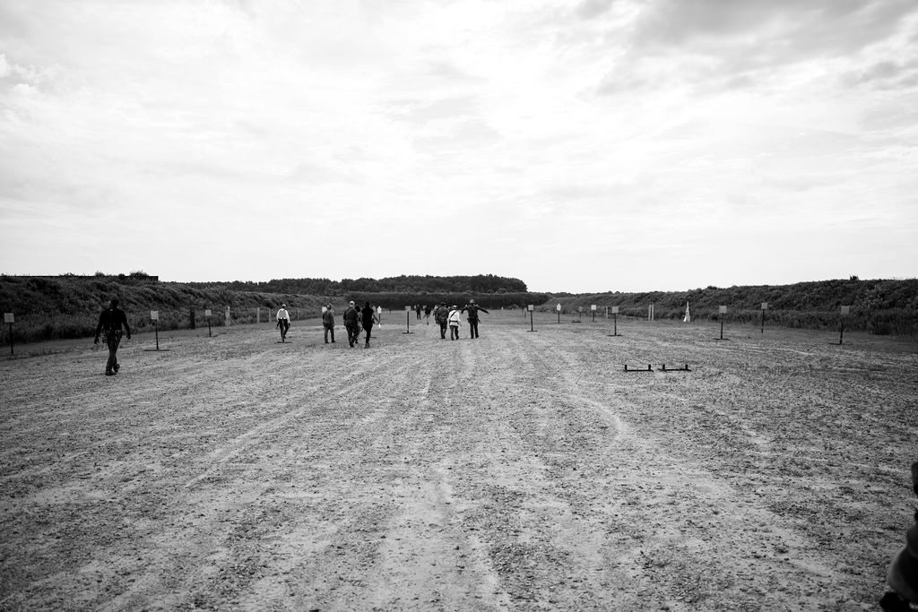 A flat open range under a wide sky, students in the distance